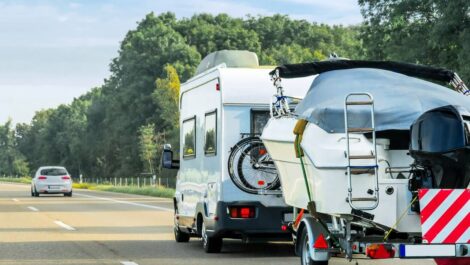 RV driving on the highway towing a boat behind.