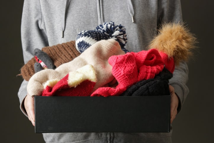 Woman holding a box of winter clothing as she cycles her items in storage.