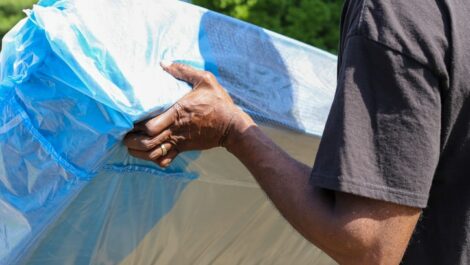 A man in a black shirt lifts a mattress.