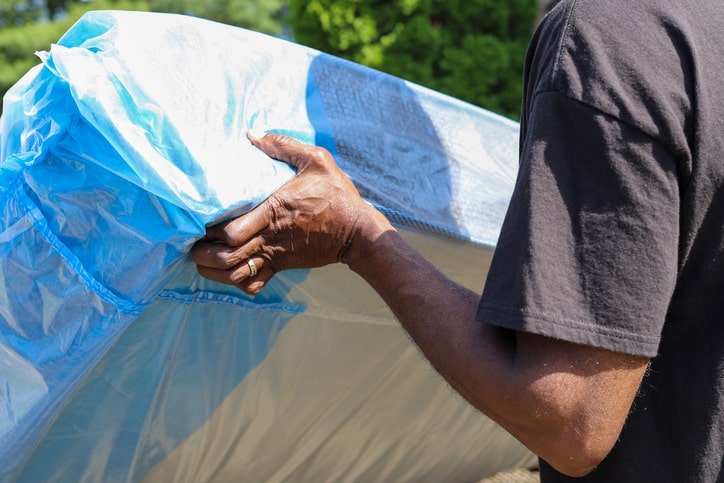 A man in a black shirt lifts a mattress.