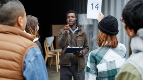 Young woman holding a number card and bidding on a container at an outdoor auction.